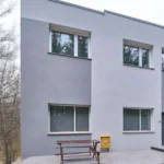 Tanie noclegi w Płocku - budynek hotelu z widocznym wejściem i miejscami parkingowymi